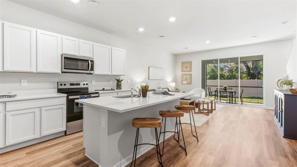 A modern kitchen with white cabinets, a central island, and sliding doors to a patio — 4040 GOLD DUST LANE, SARASOTA, FL