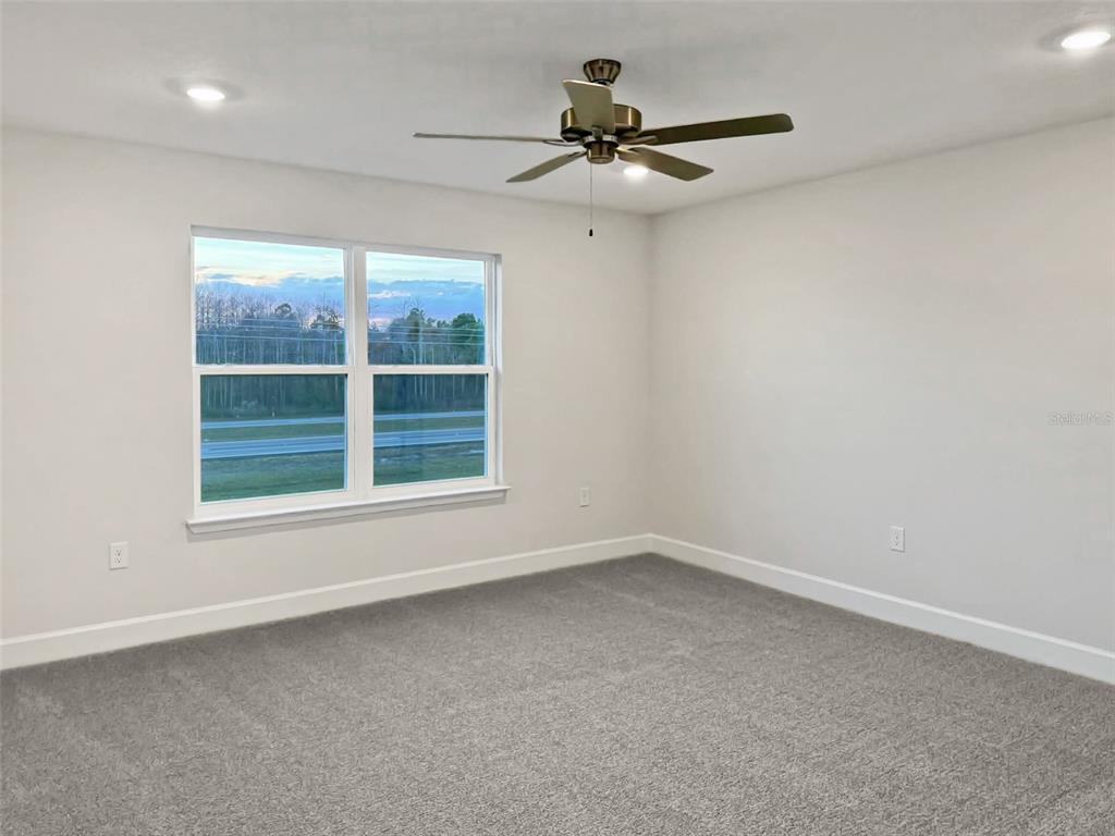 A bedroom with gray carpet, white walls, a ceiling fan, and a window — 4026 SAGEFIELD DRIVE, ST CLOUD, FL