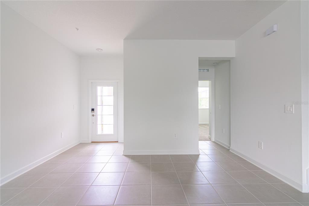 An empty room with light-colored tile flooring, white walls, and a glass-paneled entry door — 11763 BOLDFACE DRIVE, ORLANDO, FL