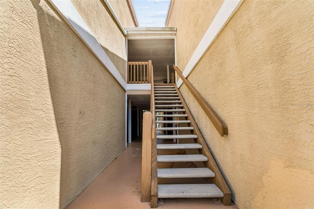 An outdoor staircase leads up to a covered landing between two stucco-walled building sections — 9481 HIGHLAND OAK DRIVE UNIT 814, TAMPA, FL