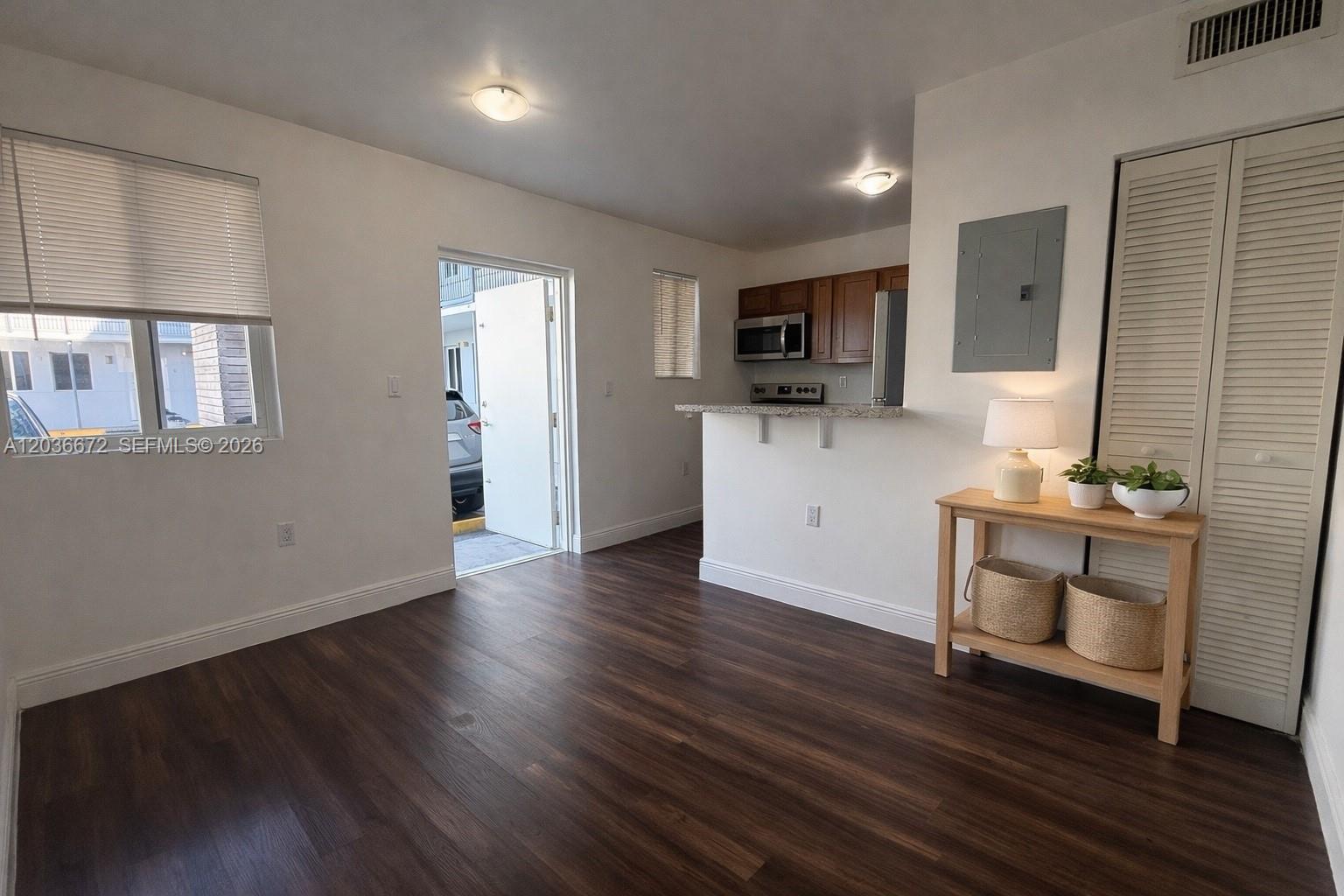 This living area features dark wood-look flooring, a kitchen pass-through, and an exterior door — 540 NW 7th St # 4, Miami FL 33136, MIAMI, FL