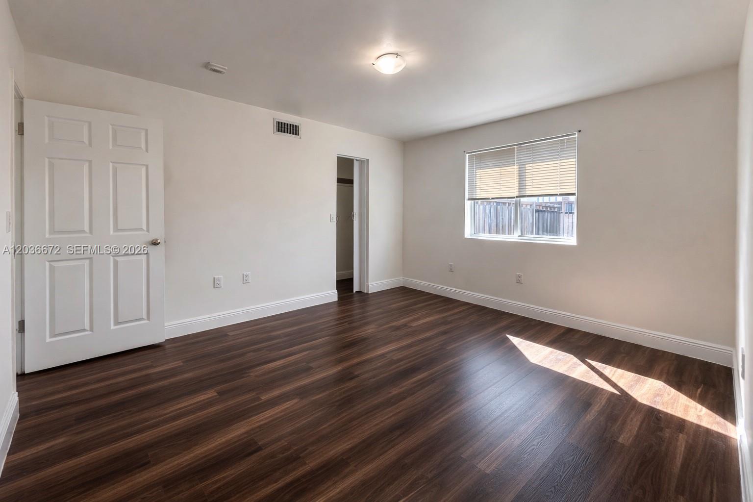 An empty bedroom features dark wood-look flooring, white walls, a window, and a closet door — 540 NW 7th St # 4, Miami FL 33136, MIAMI, FL