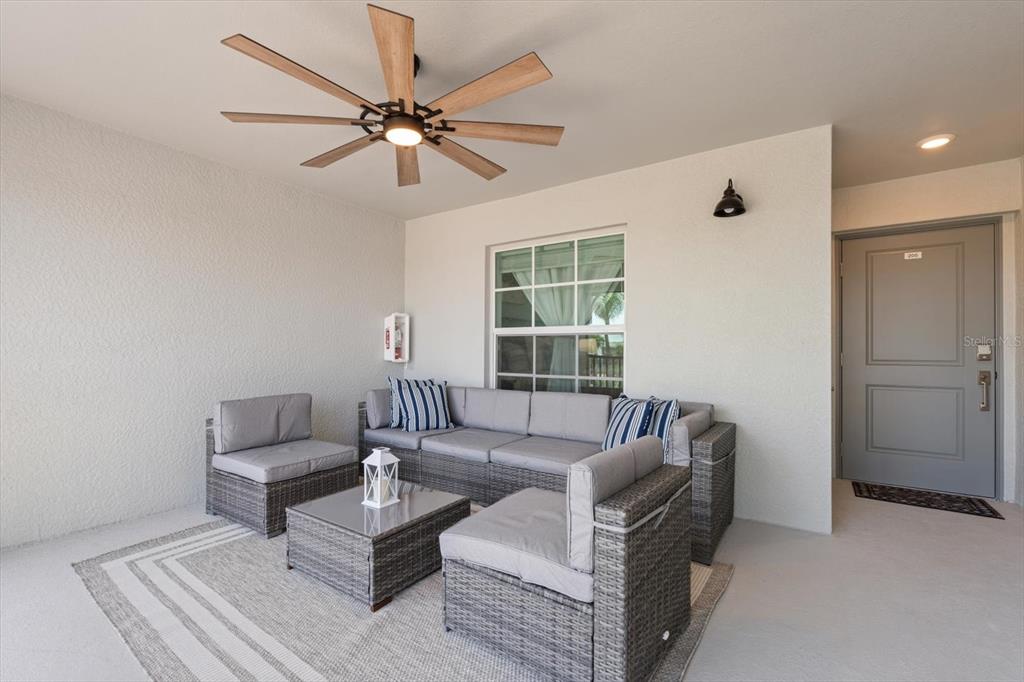A covered patio features gray wicker sectional seating, a matching coffee table, and a ceiling fan — 12470 WELLEN GOLF STREET UNIT 205, VENICE, FL