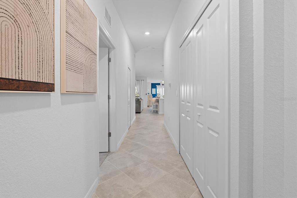 A hallway with light tile flooring leads toward an open kitchen and living area — 12470 WELLEN GOLF STREET UNIT 205, VENICE, FL