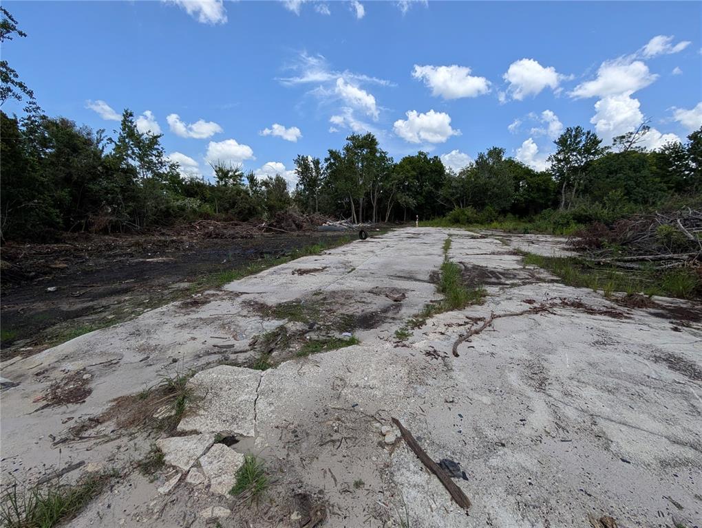 A concrete slab sits on a cleared lot surrounded by trees under a blue sky — JEFFERSON AVENUE, ORLANDO, FL