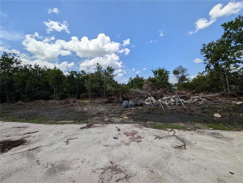 A cleared, dirt-covered lot features a concrete slab in the foreground and scattered debris — JEFFERSON AVENUE, ORLANDO, FL