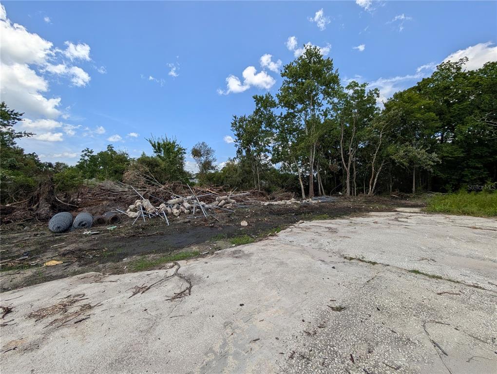A concrete slab sits next to a pile of debris and trees under a blue sky — JEFFERSON AVENUE, ORLANDO, FL