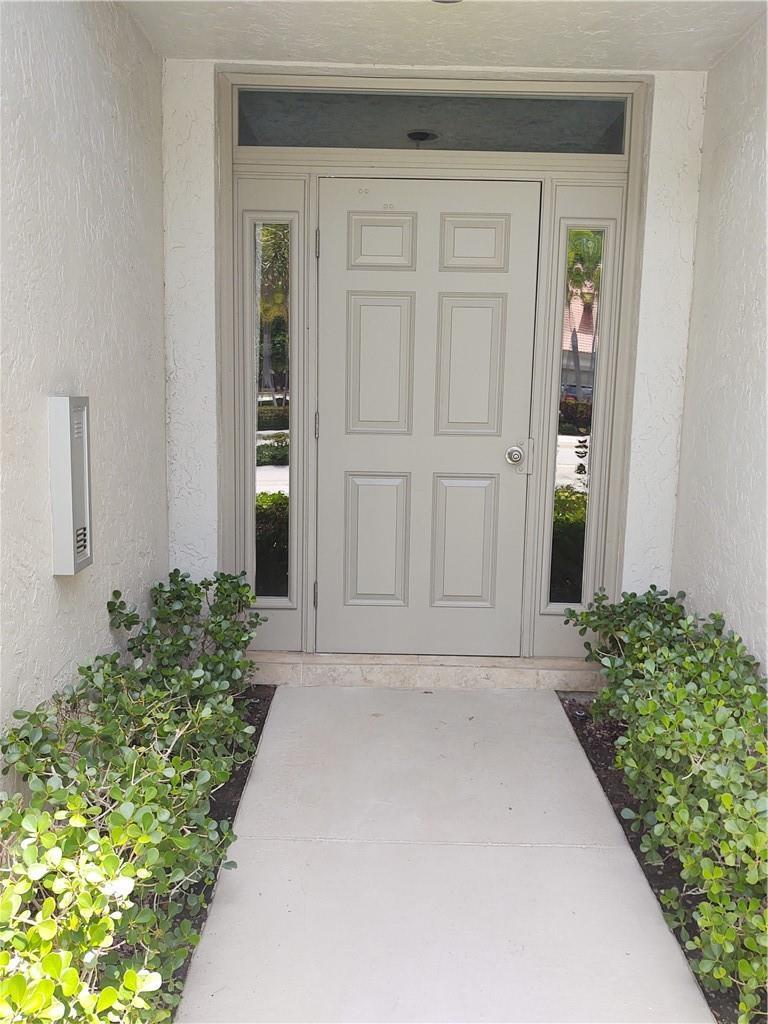A beige front door with sidelights and a transom window sits at the end of a walkway — 5801 Coach House Circle # B, Boca Raton FL 33486, BOCA RATON, FL