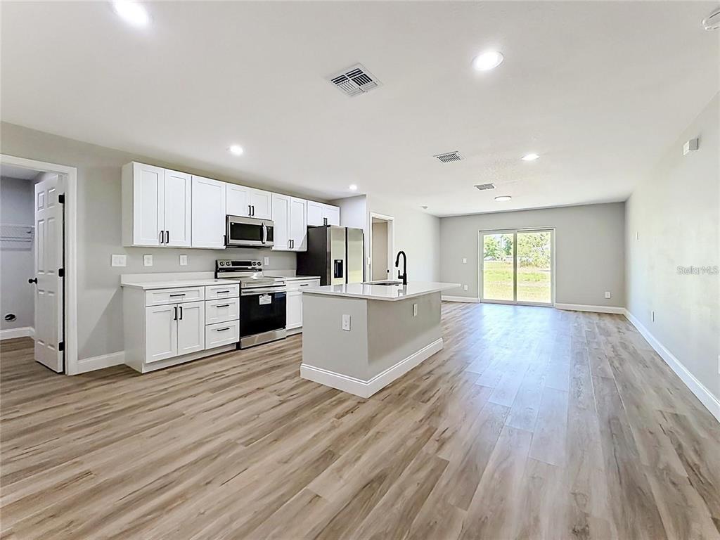 A kitchen with white cabinets, stainless steel appliances, a center island, and wood-look flooring — 44 DOGWOOD DRIVE COURSE, OCALA, FL