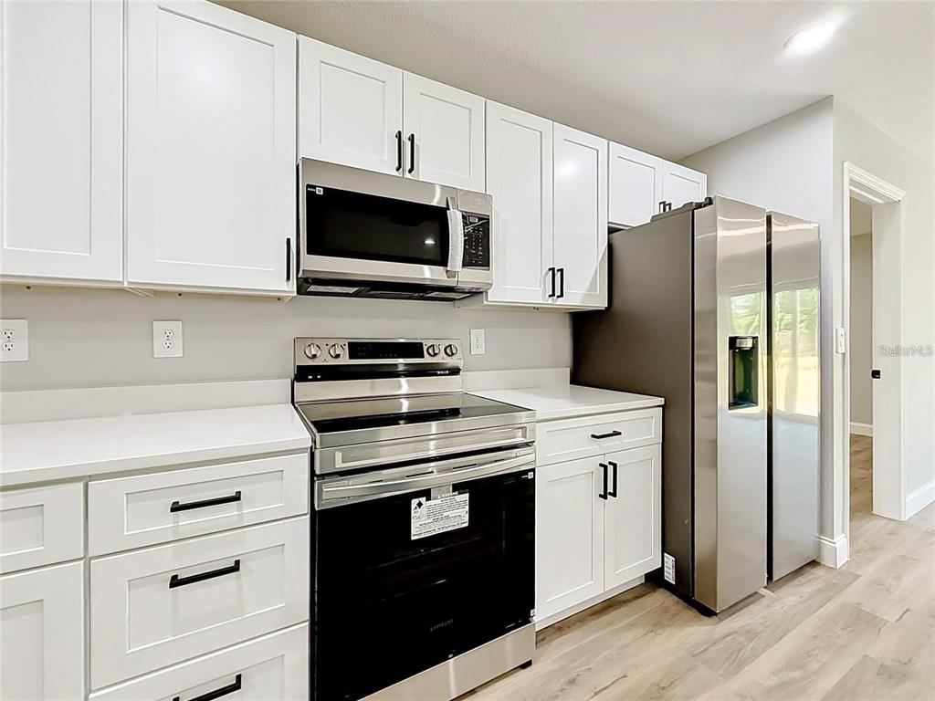 A kitchen features white cabinets, stainless steel appliances, and light-colored countertops — 44 DOGWOOD DRIVE COURSE, OCALA, FL
