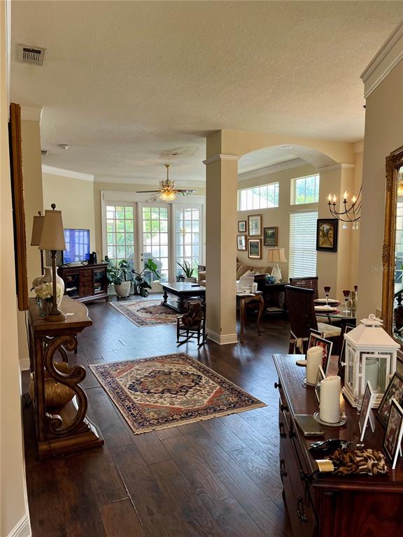 A living and dining area features dark wood floors, arched columns, and a ceiling fan — 8444 FOXWORTH CIRCLE UNIT 48, ORLANDO, FL