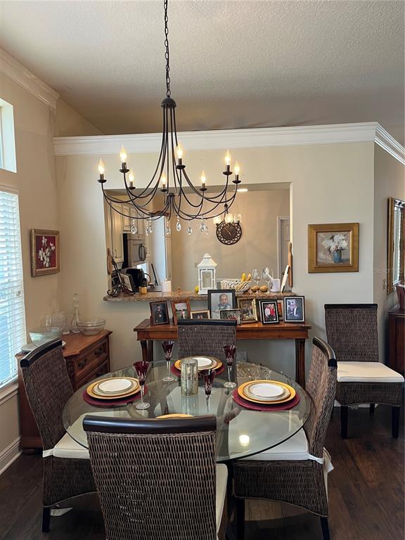 A kitchen features white cabinets, granite countertops, stainless steel appliances, and dark wood flooring — 8444 FOXWORTH CIRCLE UNIT 48, ORLANDO, FL