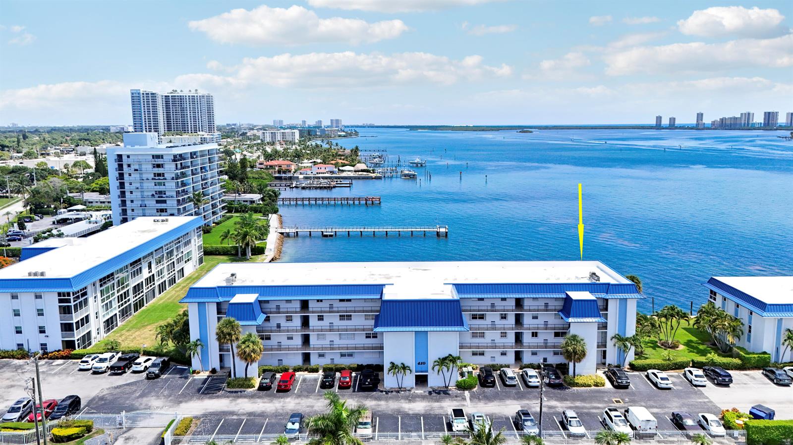 An aerial view shows a multi-story apartment building with a blue roof beside a bay — 410 Wilma Circle # 308, Riviera Beach FL 33404, RIVIERA BEACH, FL