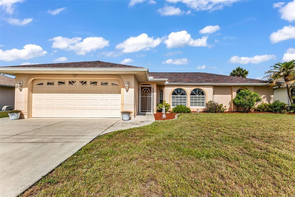 A single-story house with a beige stucco exterior, a two-car garage, and a shingled roof — 29 SEASONS DRIVE, PUNTA GORDA, FL