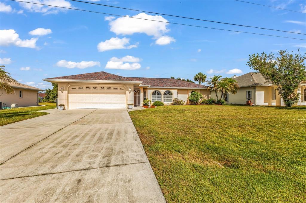 A single-story house with a two-car garage and a large front lawn under blue skies — 29 SEASONS DRIVE, PUNTA GORDA, FL