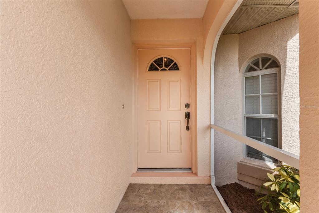 A peach-colored front door with a small arched window sits under a covered entryway — 29 SEASONS DRIVE, PUNTA GORDA, FL