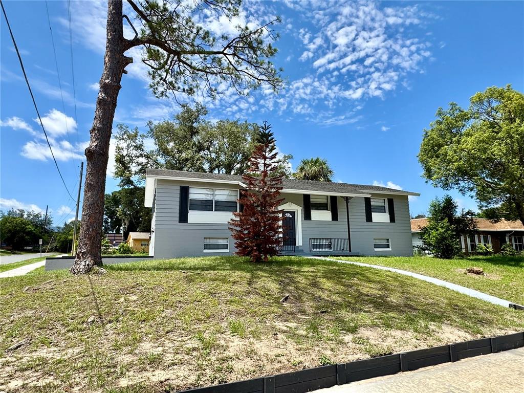 A gray single-story house with black shutters sits on a grassy, sloped lot — 6802 NAWADAHA BOULEVARD, ORLANDO, FL