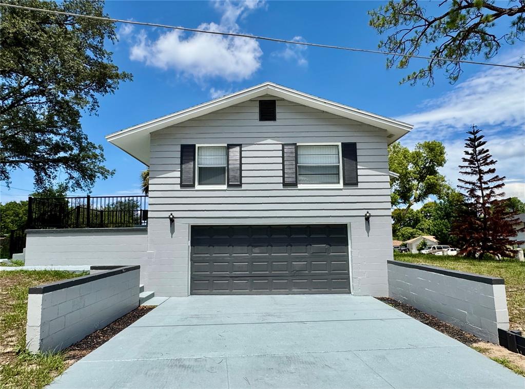 A two-story house with gray siding, a dark garage door, and a concrete driveway — 6802 NAWADAHA BOULEVARD, ORLANDO, FL