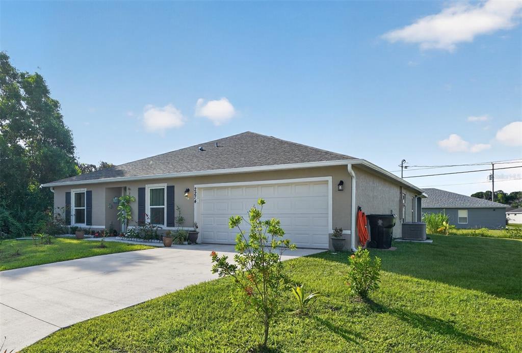 A single-story house with a beige stucco exterior, a two-car garage, and a concrete driveway — 2274 SE POWELL COURT, PORT ST LUCIE, FL