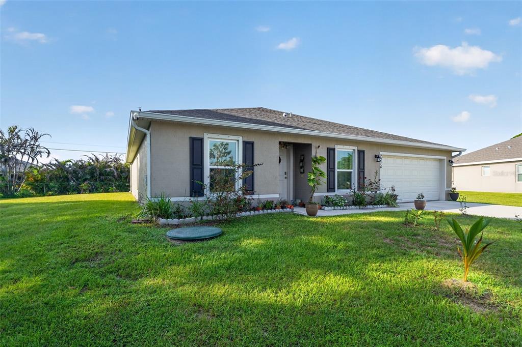 A single-story house with a beige stucco exterior, dark shutters, and an attached two-car garage — 2274 SE POWELL COURT, PORT ST LUCIE, FL