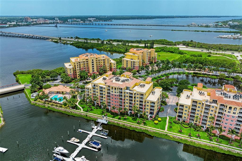 An aerial view shows several multi-story apartment buildings situated along a waterfront with boat docks — 610 RIVIERA DUNES WAY UNIT 406, PALMETTO, FL
