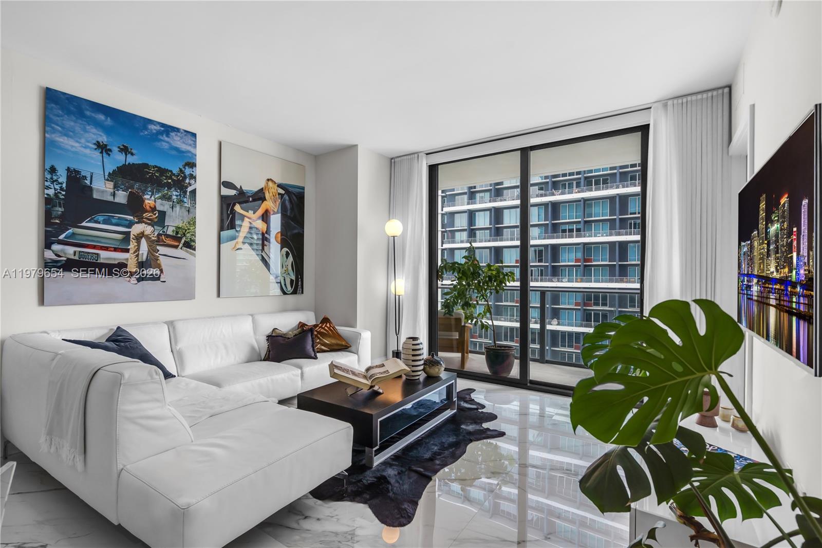 A modern living room features a white sectional sofa, marble floors, and a balcony view — 1300 S Miami Ave # 2508, Miami FL 33130, MIAMI, FL