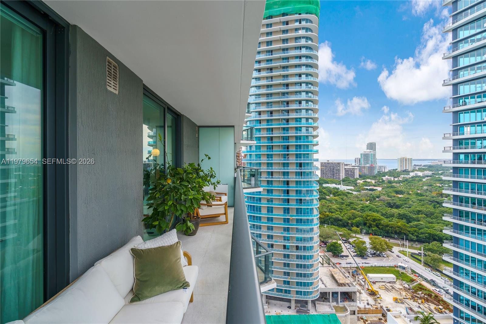 A high-rise balcony features outdoor seating, a potted plant, and views of neighboring skyscrapers — 1300 S Miami Ave # 2508, Miami FL 33130, MIAMI, FL