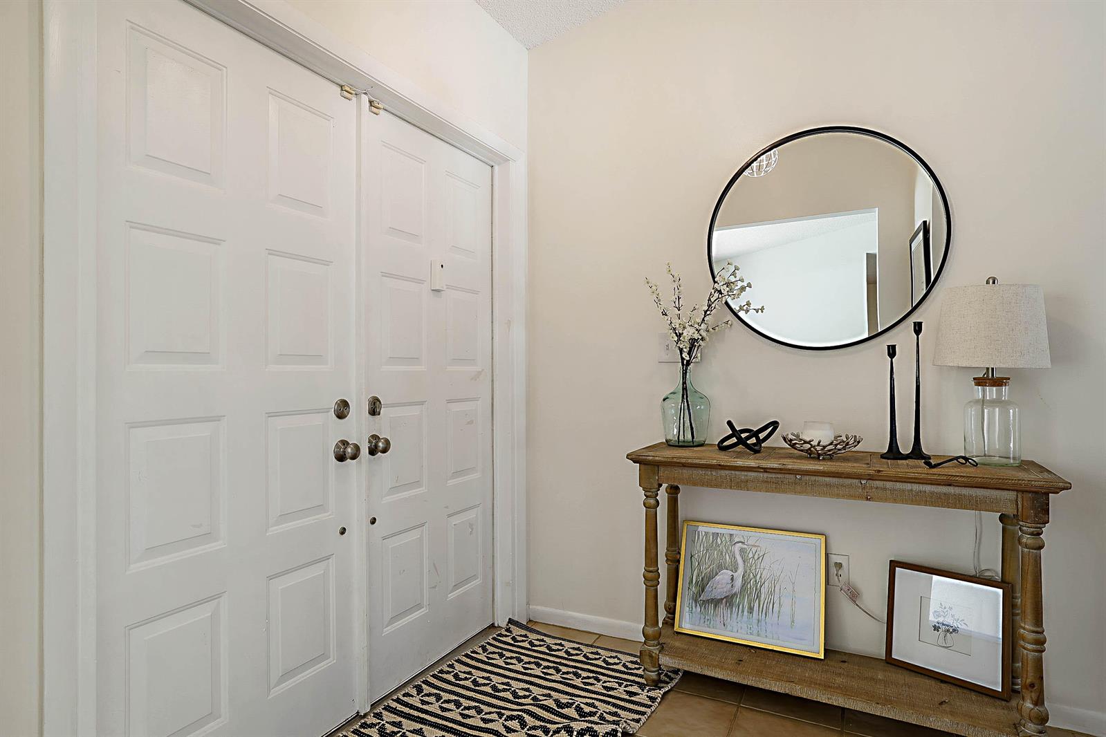 A foyer features double white doors, a wooden console table, and a round wall mirror — 20869 Sonrisa Way, Boca Raton FL 33433, BOCA RATON, FL