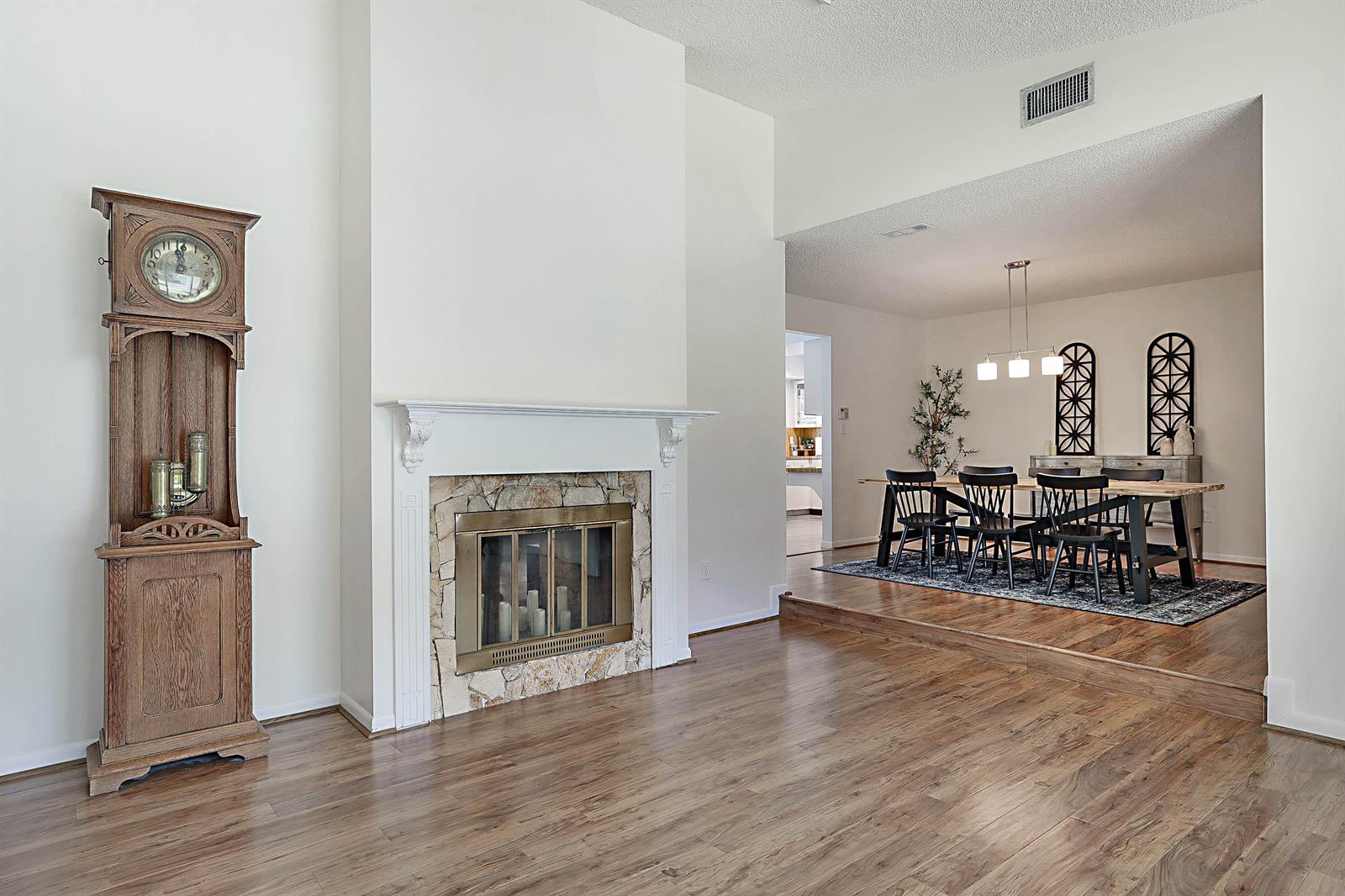 A living room with a stone fireplace and grandfather clock overlooks a raised dining area — 20869 Sonrisa Way, Boca Raton FL 33433, BOCA RATON, FL