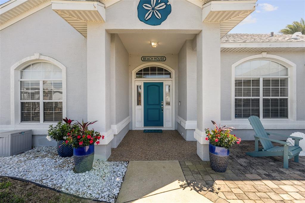 The exterior of a house features a teal front door, a sand dollar decoration, and planters — 20 MOODY DRIVE, PALM COAST, FL
