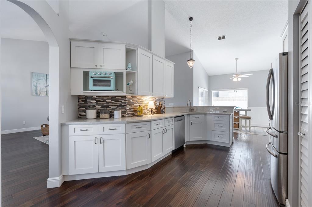 A kitchen with white cabinets, stainless steel appliances, a mosaic backsplash, and dark wood flooring — 20 MOODY DRIVE, PALM COAST, FL