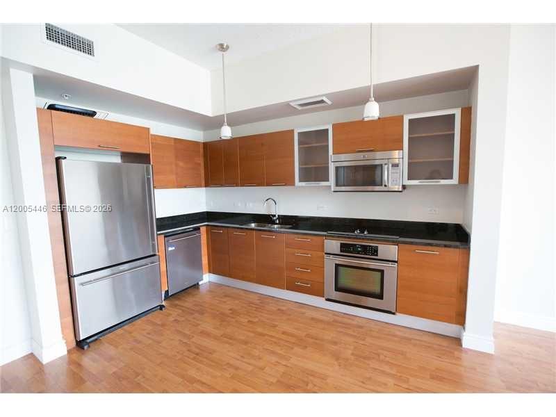 A modern kitchen features wood cabinets, stainless steel appliances, and dark countertops — 3470 E Coast Ave # H1503, Miami FL 33137, MIAMI, FL