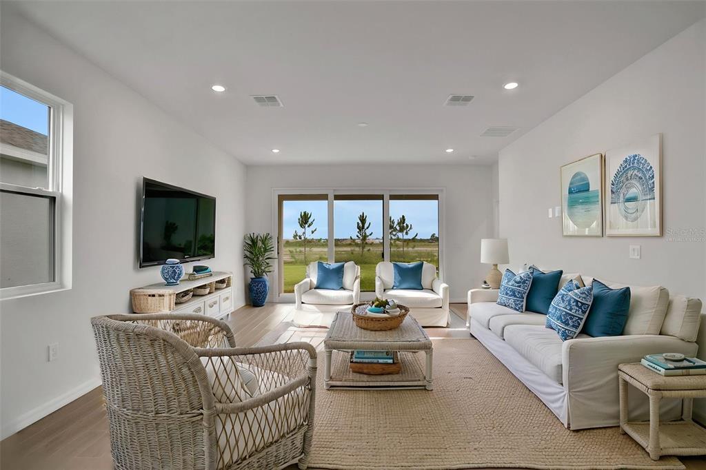 A bright living room features a white sofa, wicker chairs, and large sliding glass doors — 8112 SUNNY POINT TRAIL, PARRISH, FL