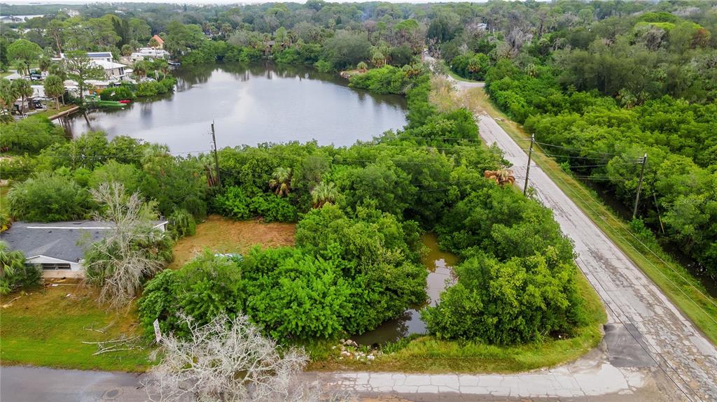 An aerial view shows a vacant lot with trees and a small pond near a road — 4935 LARGO TERRACE, NEW PORT RICHEY, FL
