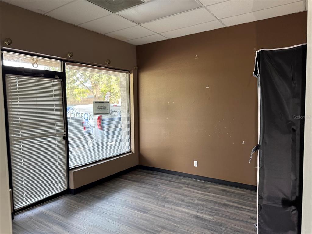 An empty commercial office space features brown walls, wood-look flooring, and a large front window — 821 NE 36TH TERRACE UNIT 7/8/9, OCALA, FL