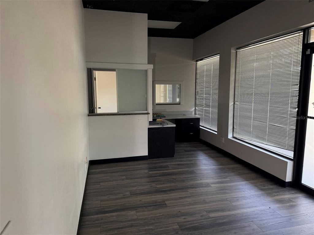 An office space features dark wood-look flooring, a service window, and large windows with blinds — 821 NE 36TH TERRACE UNIT 7/8/9, OCALA, FL