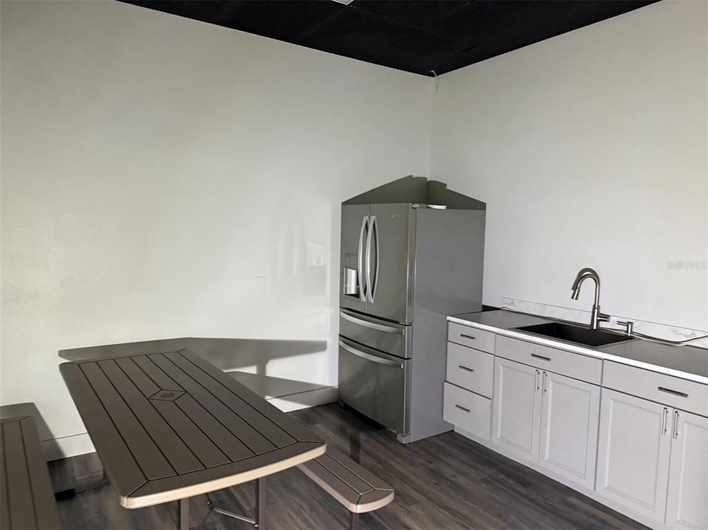 A kitchen area features a stainless steel refrigerator, white cabinets, a sink, and a dining table — 821 NE 36TH TERRACE UNIT 7/8/9, OCALA, FL
