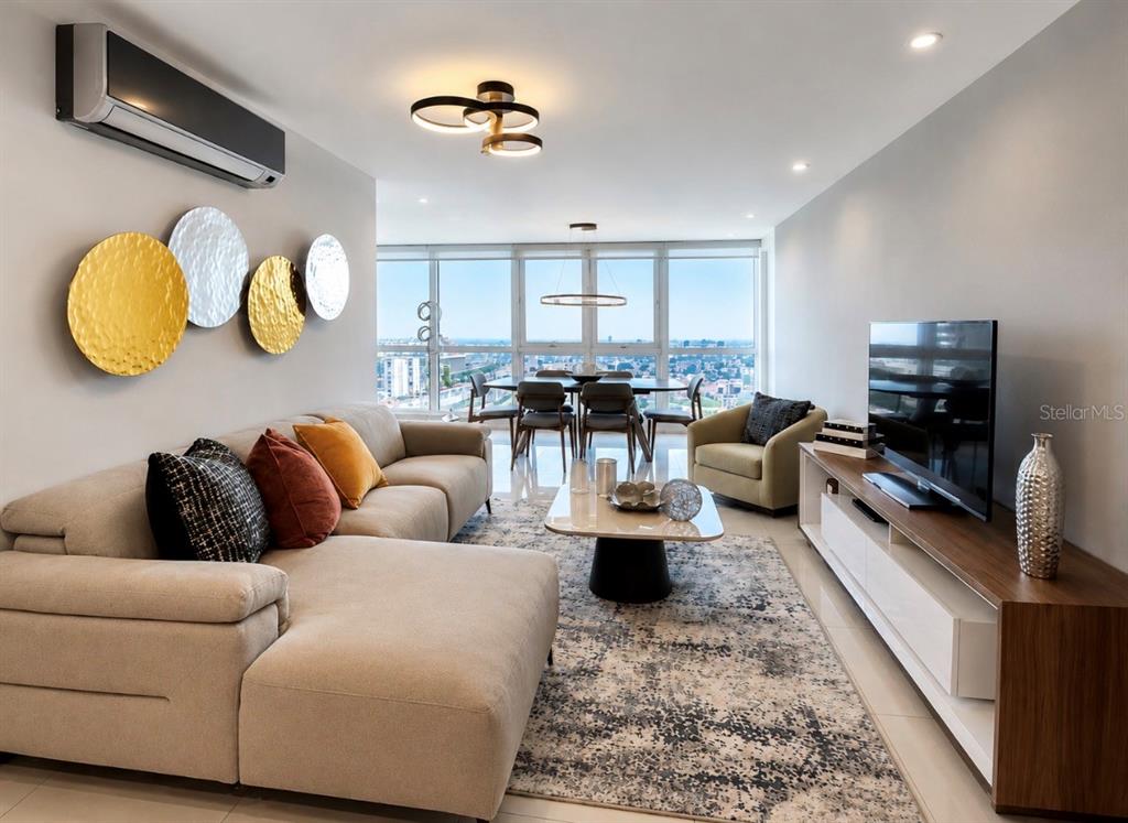 A modern living room features a beige sectional sofa, a television, and floor-to-ceiling windows — 48 LUIS MUÑOZ RIVERA UNIT 2202, SAN JUAN, PR