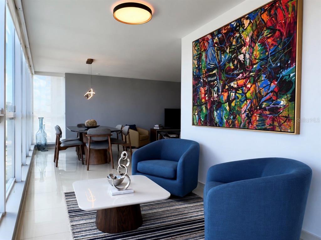 A living and dining area features blue armchairs, a white coffee table, and abstract art — 48 LUIS MUÑOZ RIVERA UNIT 2202, SAN JUAN, PR