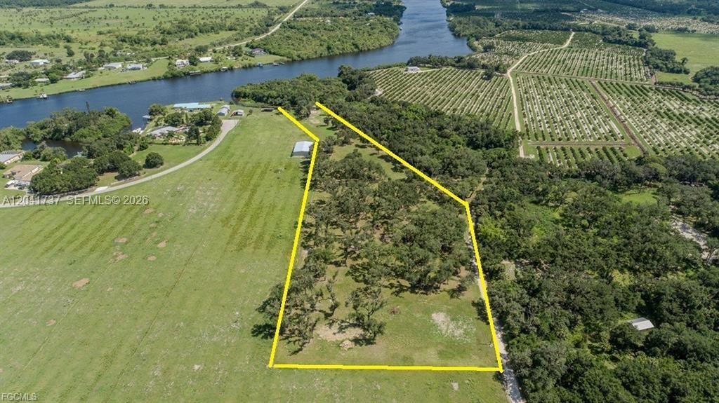 An aerial view shows a rectangular plot of land outlined in yellow near a river — 5247 County Road 78, La Belle FL 33935, LA BELLE, FL
