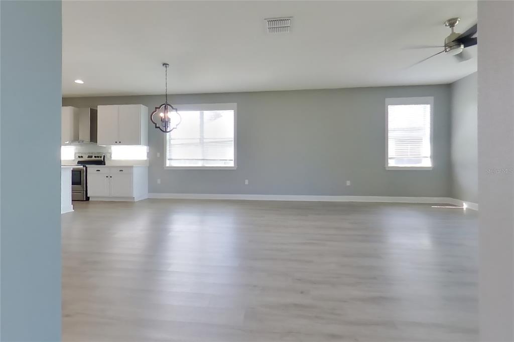 An open-concept living area features light gray walls, white cabinetry, and light wood-look flooring — 2416 SABASTIAN STREET, MOUNT DORA, FL