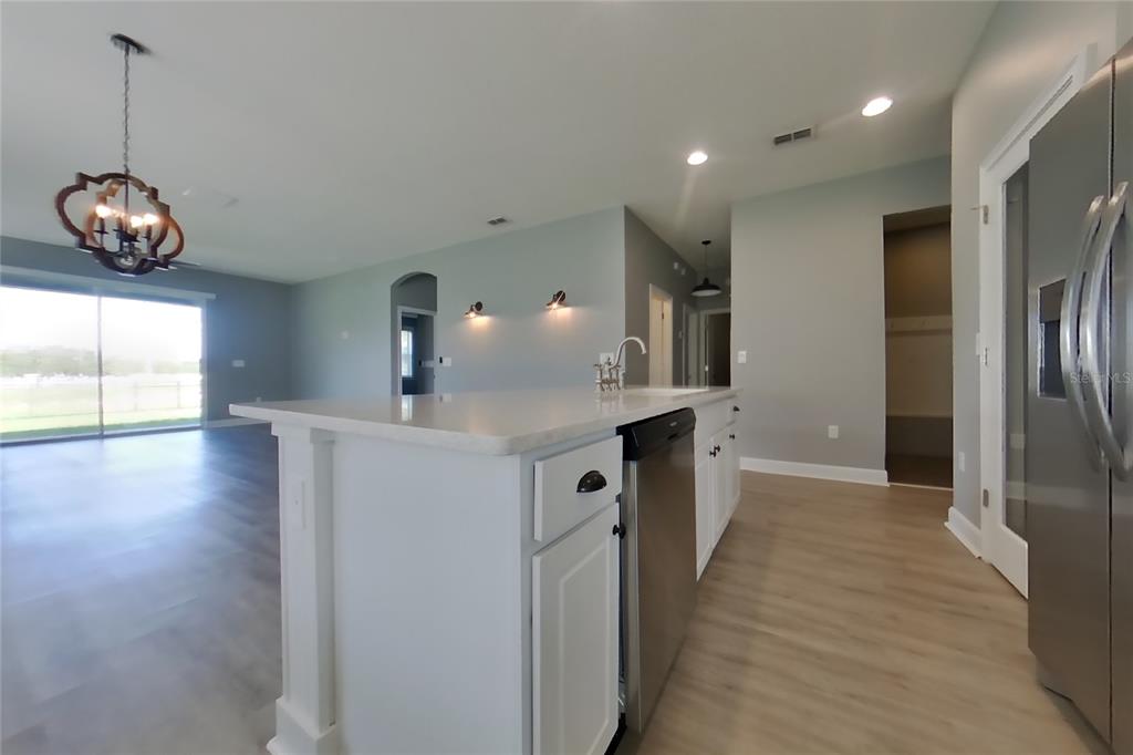 A kitchen island with a stainless steel dishwasher sits in an open-concept living area — 2416 SABASTIAN STREET, MOUNT DORA, FL