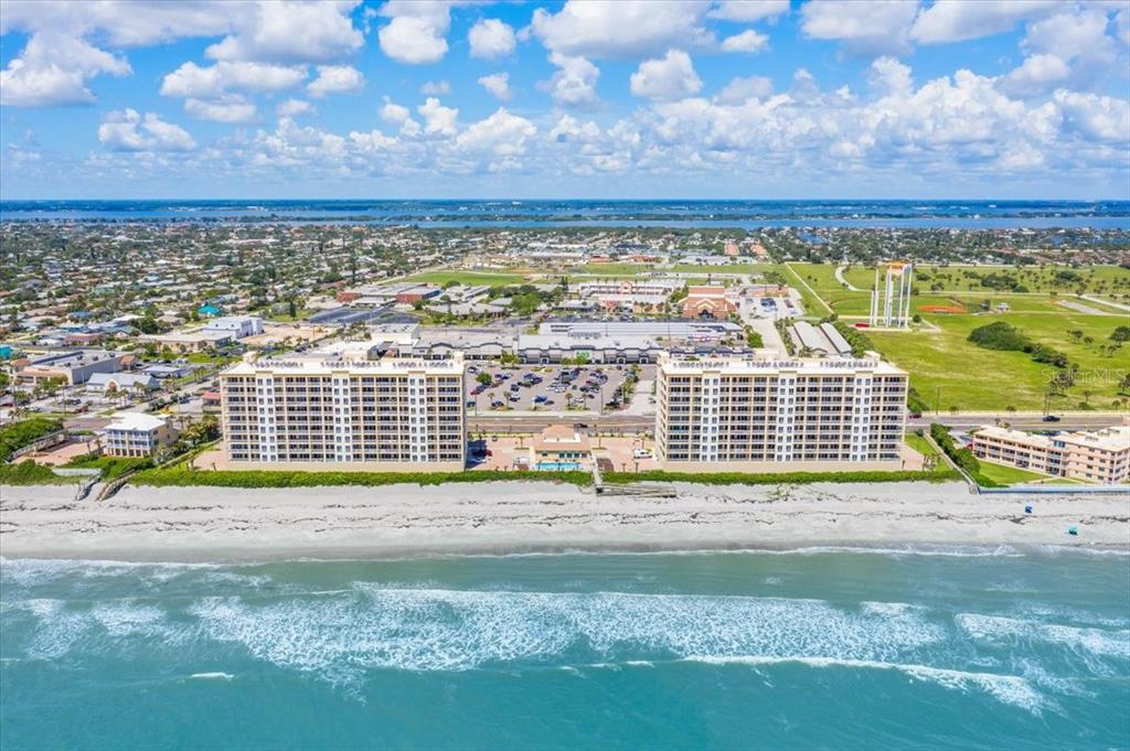 An aerial view of two large beachfront condominium buildings along a sandy coastline — 1025 HIGHWAY A1A UNIT 406, SATELLITE BEACH, FL