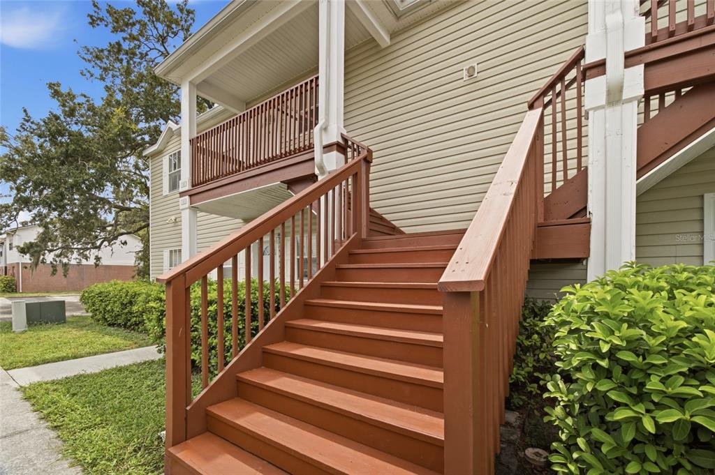 Exterior view of a wooden staircase leading to an upper-level balcony of a residential building — 9019 COCHISE LANE UNIT 201, PORT RICHEY, FL