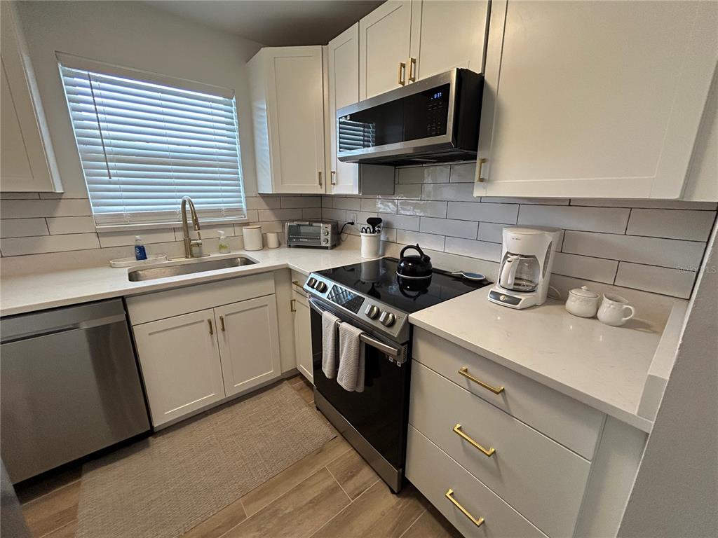 A kitchen features white cabinets, stainless steel appliances, a subway tile backsplash, and quartz countertops — 4480 IRONWOOD CIRCLE UNIT 213A, BRADENTON, FL