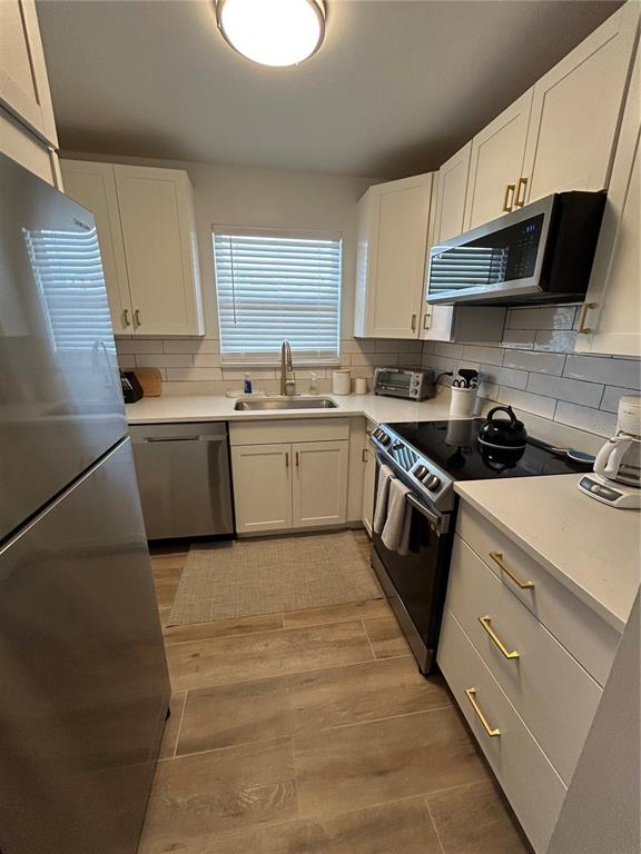 A kitchen features white cabinets, stainless steel appliances, a subway tile backsplash, and wood-look flooring — 4480 IRONWOOD CIRCLE UNIT 213A, BRADENTON, FL