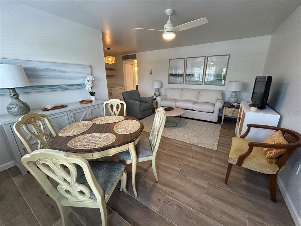 A dining area and living room feature light wood-look flooring and neutral furniture — 4480 IRONWOOD CIRCLE UNIT 213A, BRADENTON, FL