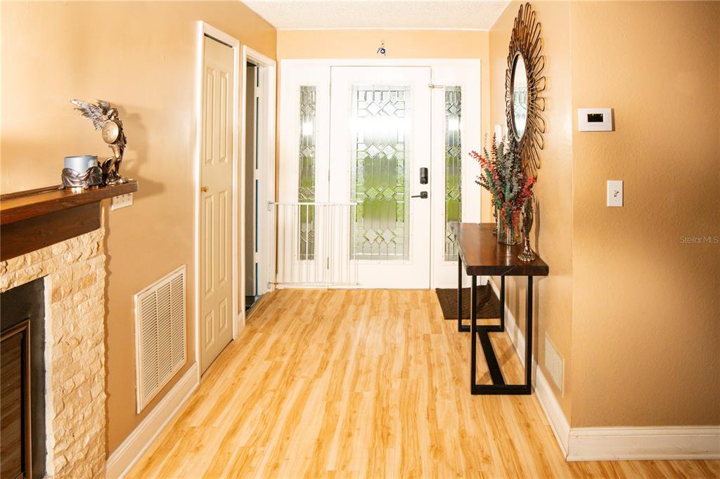 An entryway features light wood-look flooring, a white front door, and a wooden console table — 5834 98TH AVENUE N, PINELLAS PARK, FL