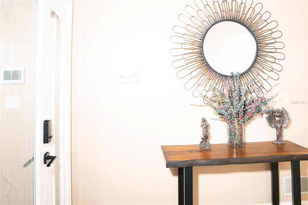 A wooden console table with a sunburst mirror and decor sits in an entryway — 5834 98TH AVENUE N, PINELLAS PARK, FL