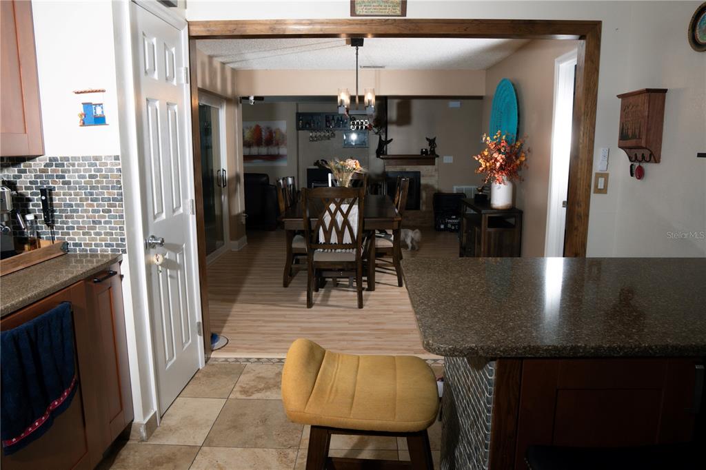 A kitchen with a breakfast bar overlooks a dining room with a wooden table — 5834 98TH AVENUE N, PINELLAS PARK, FL